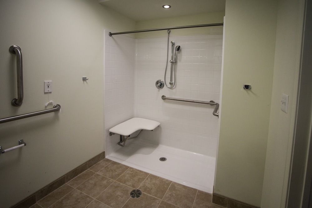 An accessible shower with grab bars and a folding seat.