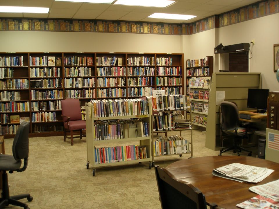 A cozy library interior with shelves full of books and a reading area.