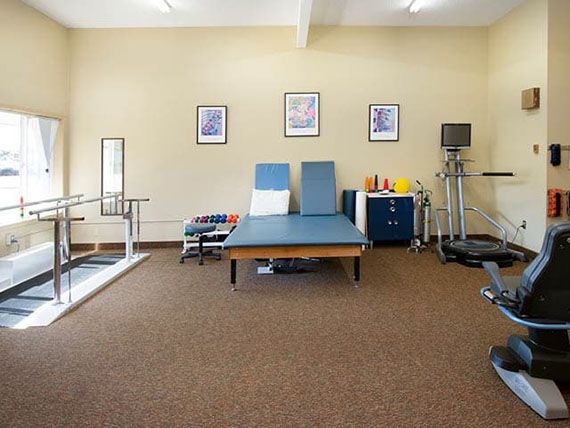 A well-equipped physical therapy room featuring a treatment table and various exercise equipment.