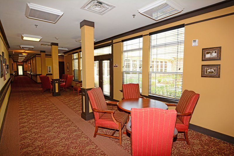A cozy dining area with several tables and chairs, featuring large windows and soft lighting.