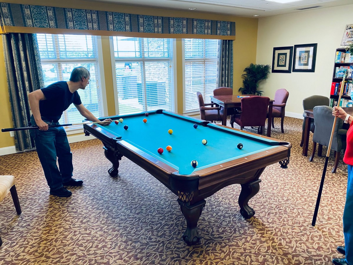 A person playing billiards in a cozy game room.