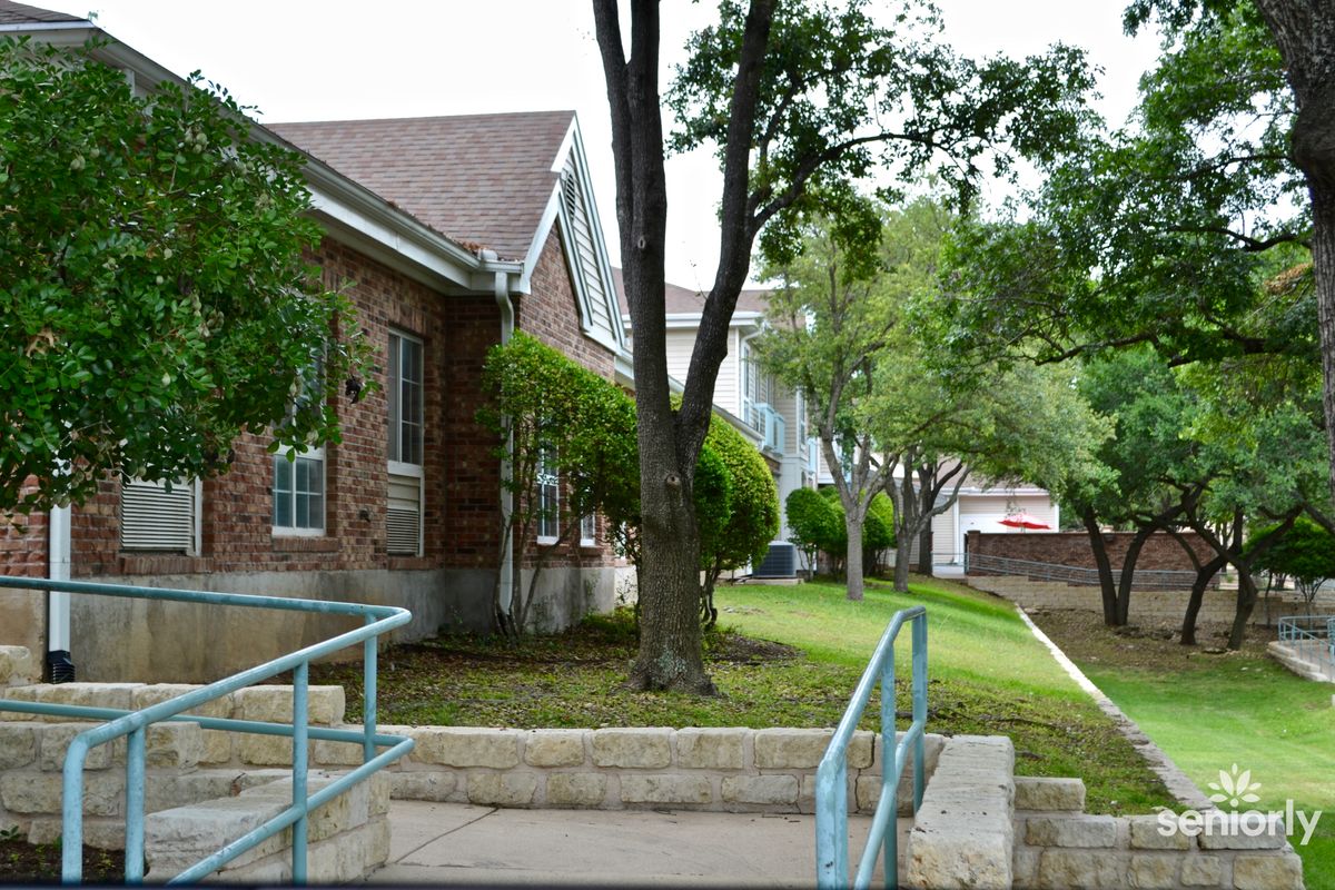 A brick building surrounded by trees and a sidewalk with an accessibility ramp.