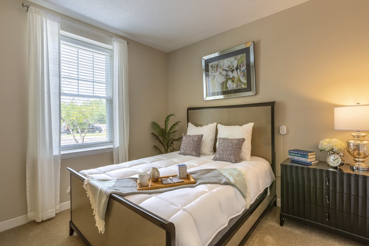 A cozy and well-decorated bedroom with a neatly made bed, soft lighting, and a tray placed on the bed for added comfort.