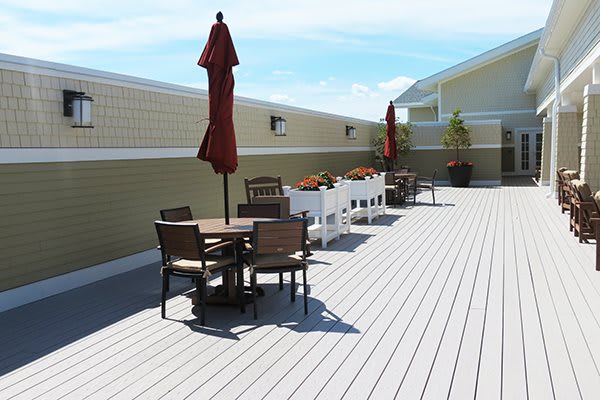 A spacious outdoor deck with seating areas and red umbrellas, perfect for relaxation on a sunny day.