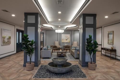 A modern lobby with a central fountain and seating area.