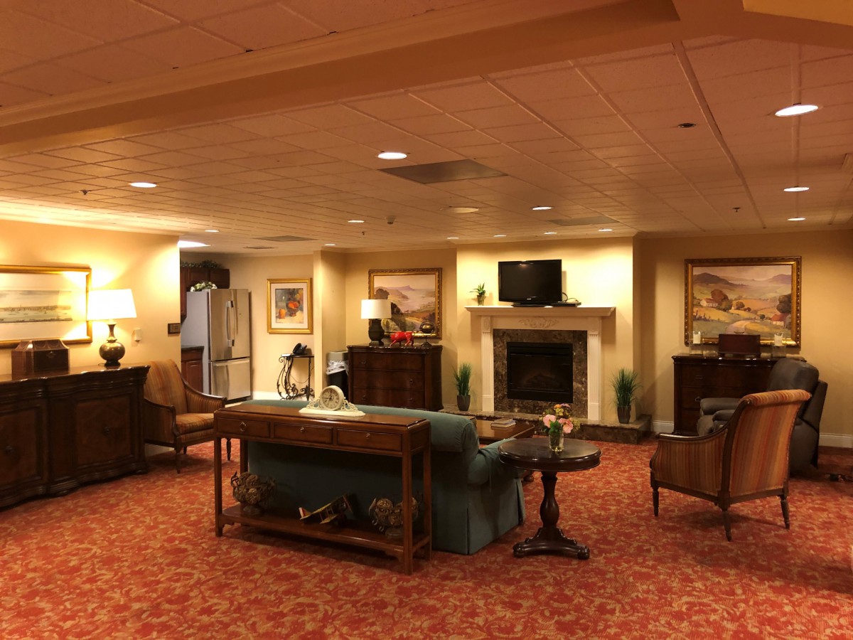 A warmly lit lobby featuring comfortable seating, a fireplace, and decorative artwork.