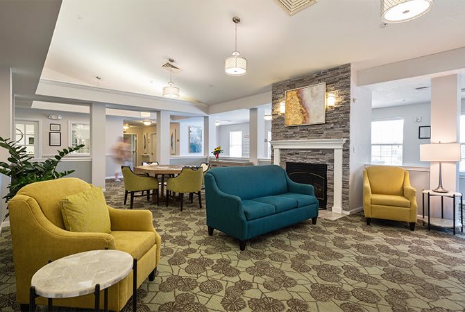 A modern living room with colorful sofas, a fireplace, and decorative artwork.