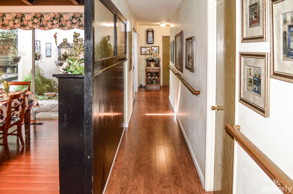 A hallway with wooden flooring and handrails, adorned with paintings on the walls.
