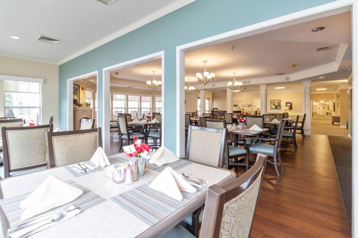 A well-lit dining area with neatly arranged tables and chairs, set for guests.