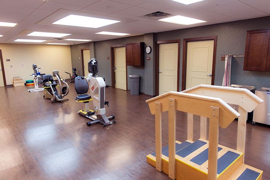 A fitness room equipped with various exercise machines and a set of therapy stairs.