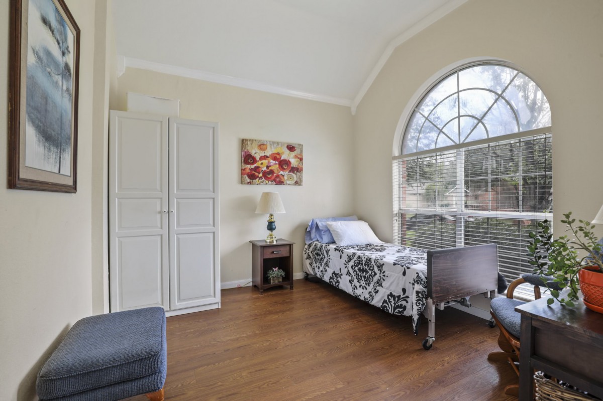 A bright bedroom with a single bed, large arched window, and minimalist decor.