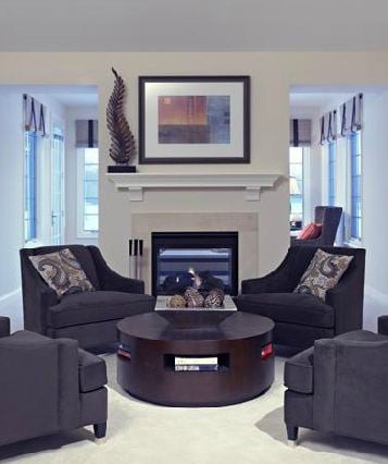A modern living room with a central fireplace, surrounded by dark upholstered chairs and stylish decor.