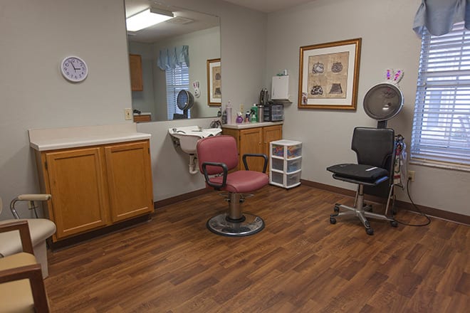 A cozy hair salon with a barber chair and mirror, featuring wooden flooring.