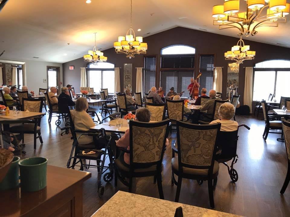 A dining area with seniors seated at tables, featuring elegant lighting and a warm atmosphere.