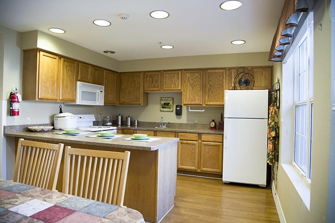 A modern kitchen with wooden cabinets, a refrigerator, and a microwave, complete with a dining table.