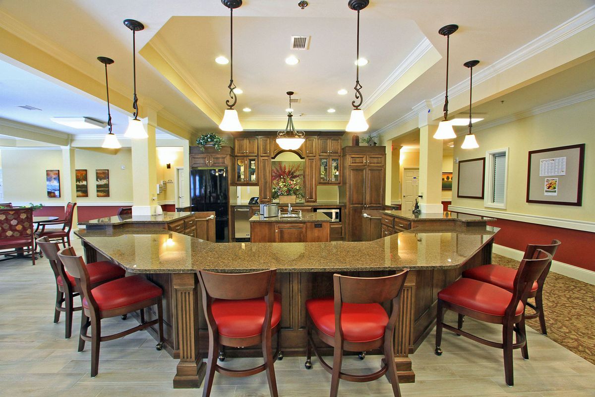 Spacious kitchen area with a central island, featuring red cushioned bar stools and elegant pendant lighting.