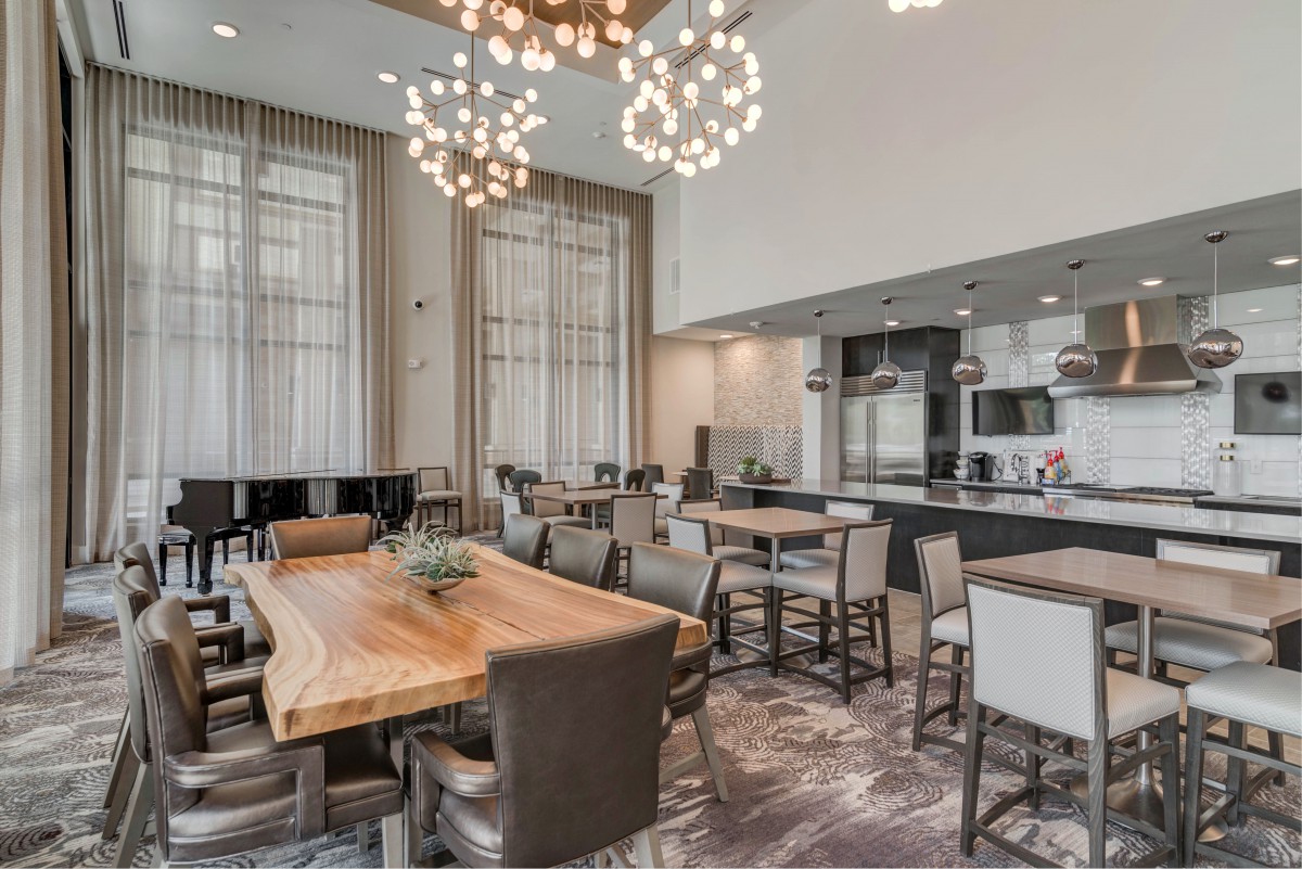 A modern dining area with a large wooden table and stylish chandeliers.