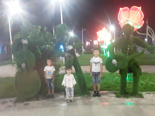 A fun night at the park with children posing alongside whimsical topiary figures.