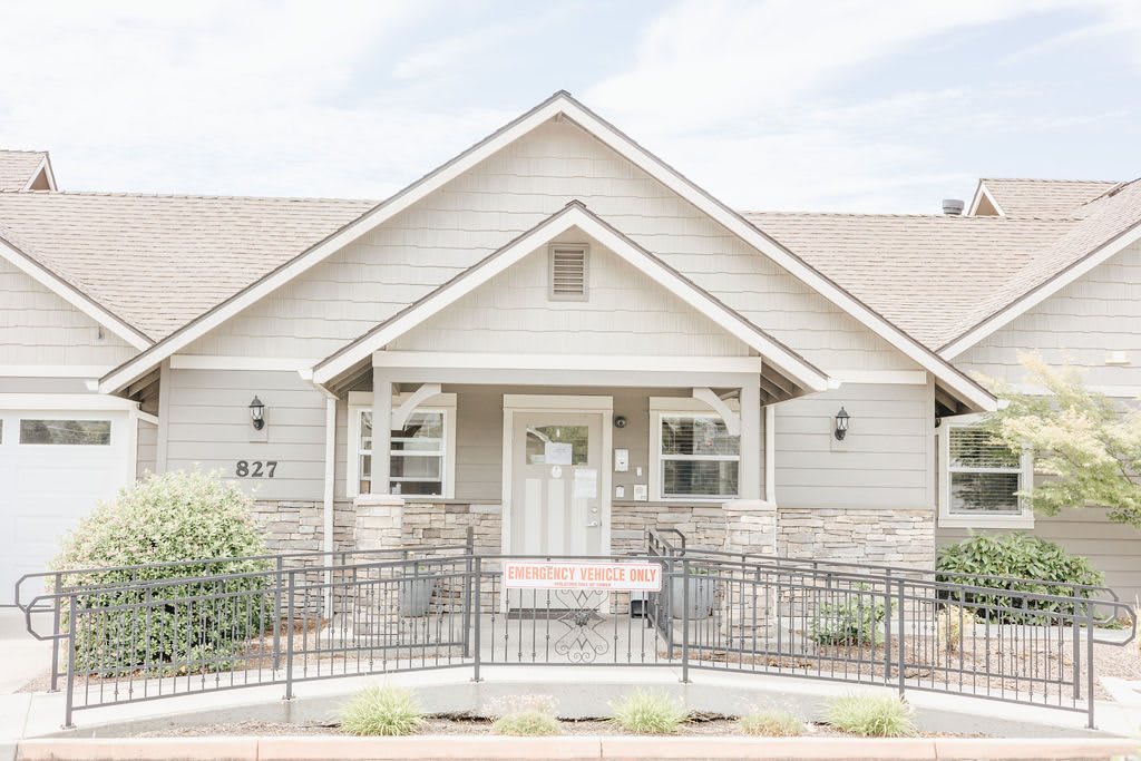 A charming residential house with a gabled roof and a fenced front yard.