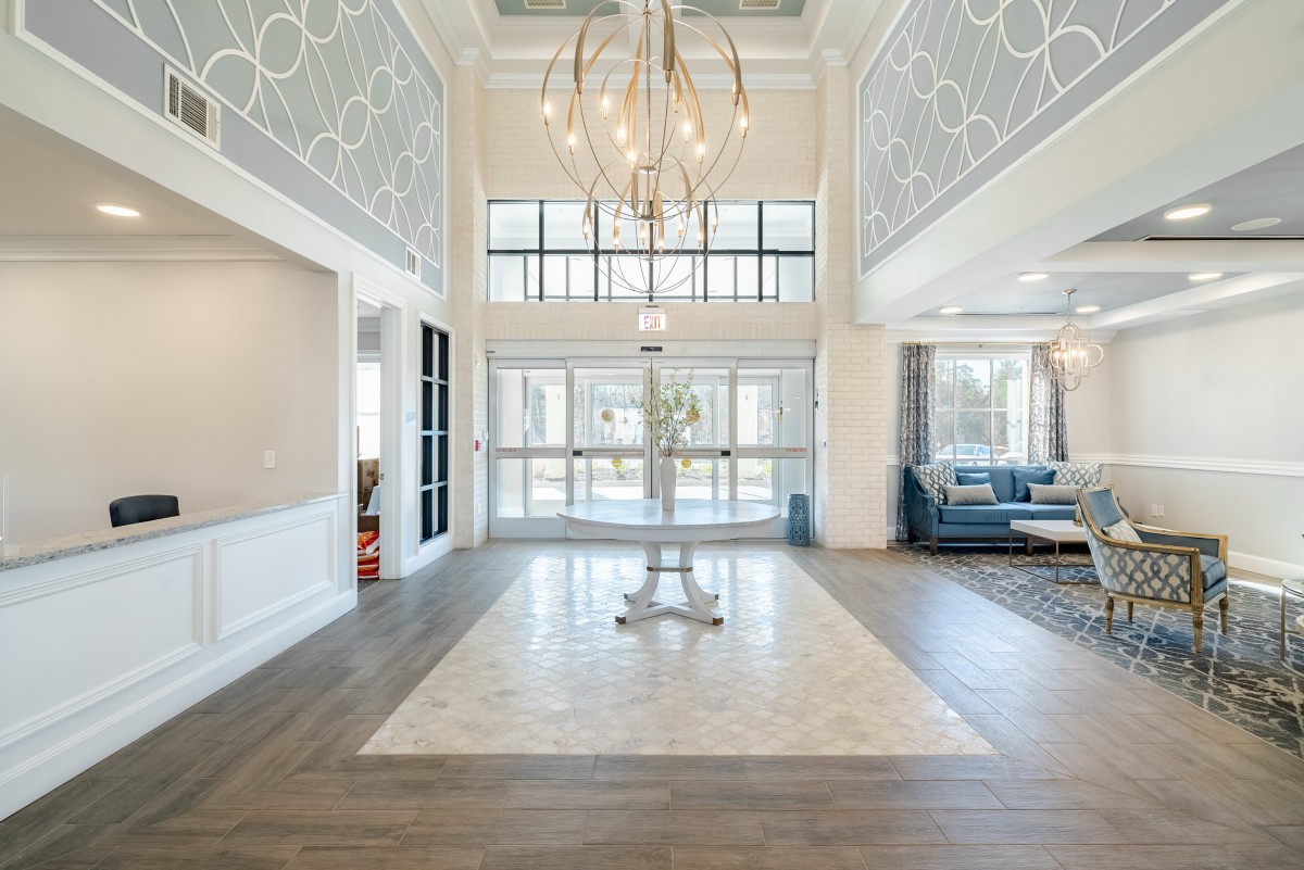A spacious and elegantly designed lobby area with a modern chandelier and large windows.