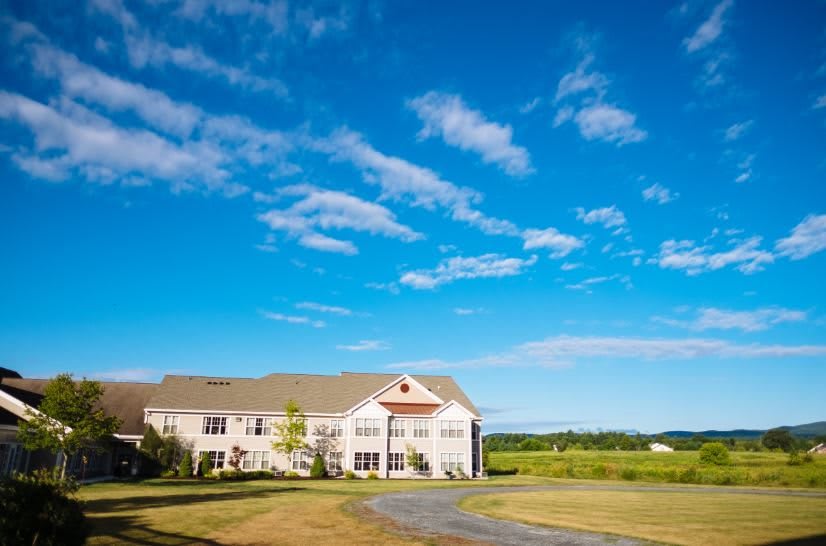 A tranquil view of a house under a bright blue sky with scattered clouds.