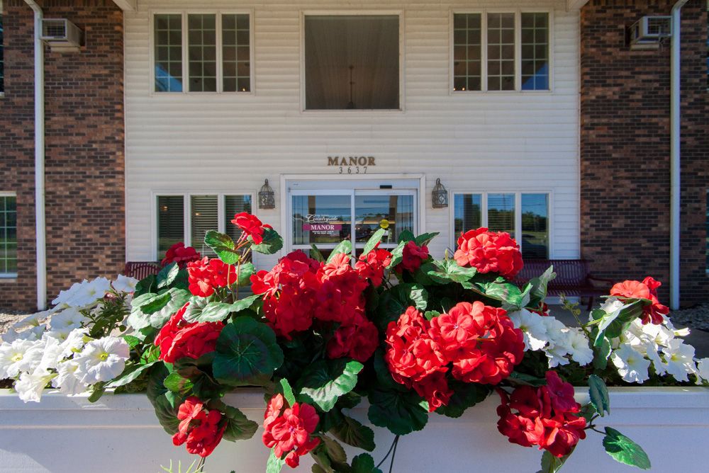 A close-up of vibrant red roses in front of a building entrance.