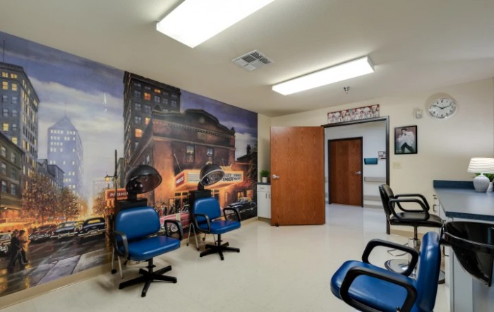 A waiting room with blue chairs and a mural on the wall depicting an urban scene.