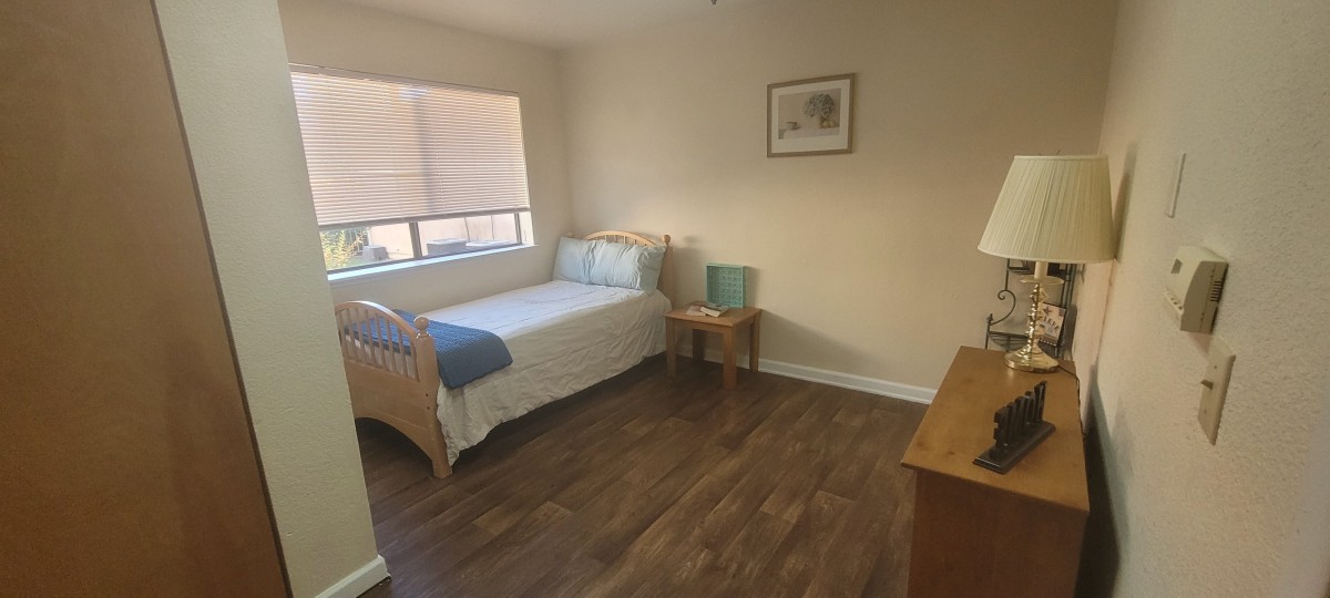 A simple and cozy bedroom with a single bed and wooden flooring.