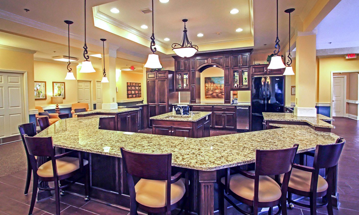 A modern kitchen with granite countertops, wood cabinets, and bar stools.