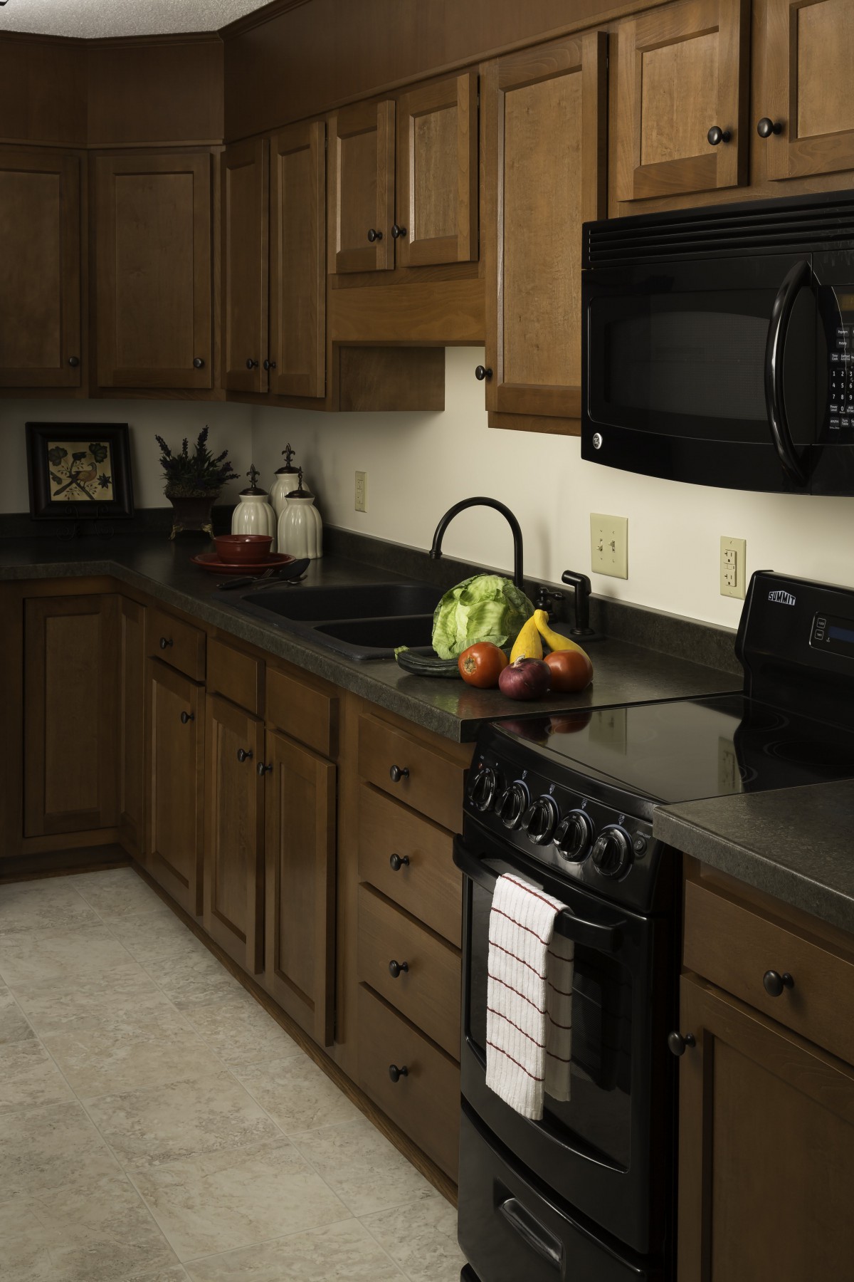 A cozy kitchen with wooden cabinets, a black countertop, and various appliances.