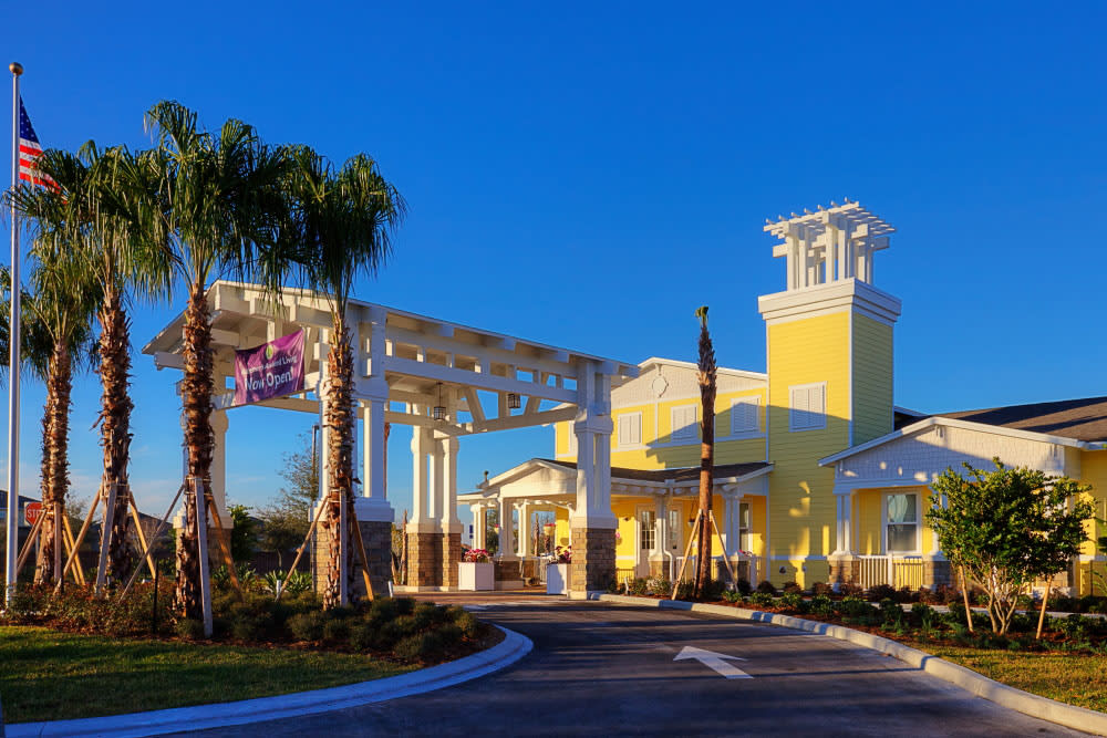 A sunny view of a resort entrance with palm trees and bright yellow architecture.