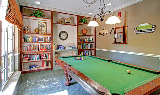 A cozy game room featuring a green pool table and bookshelves, perfect for relaxation and entertainment.