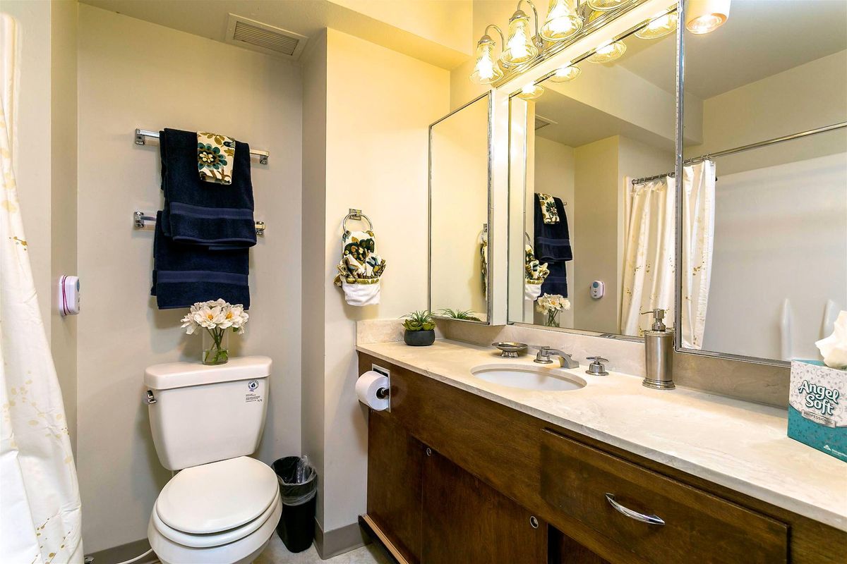 A neatly organized bathroom with a large mirror, sink, and decorative elements.