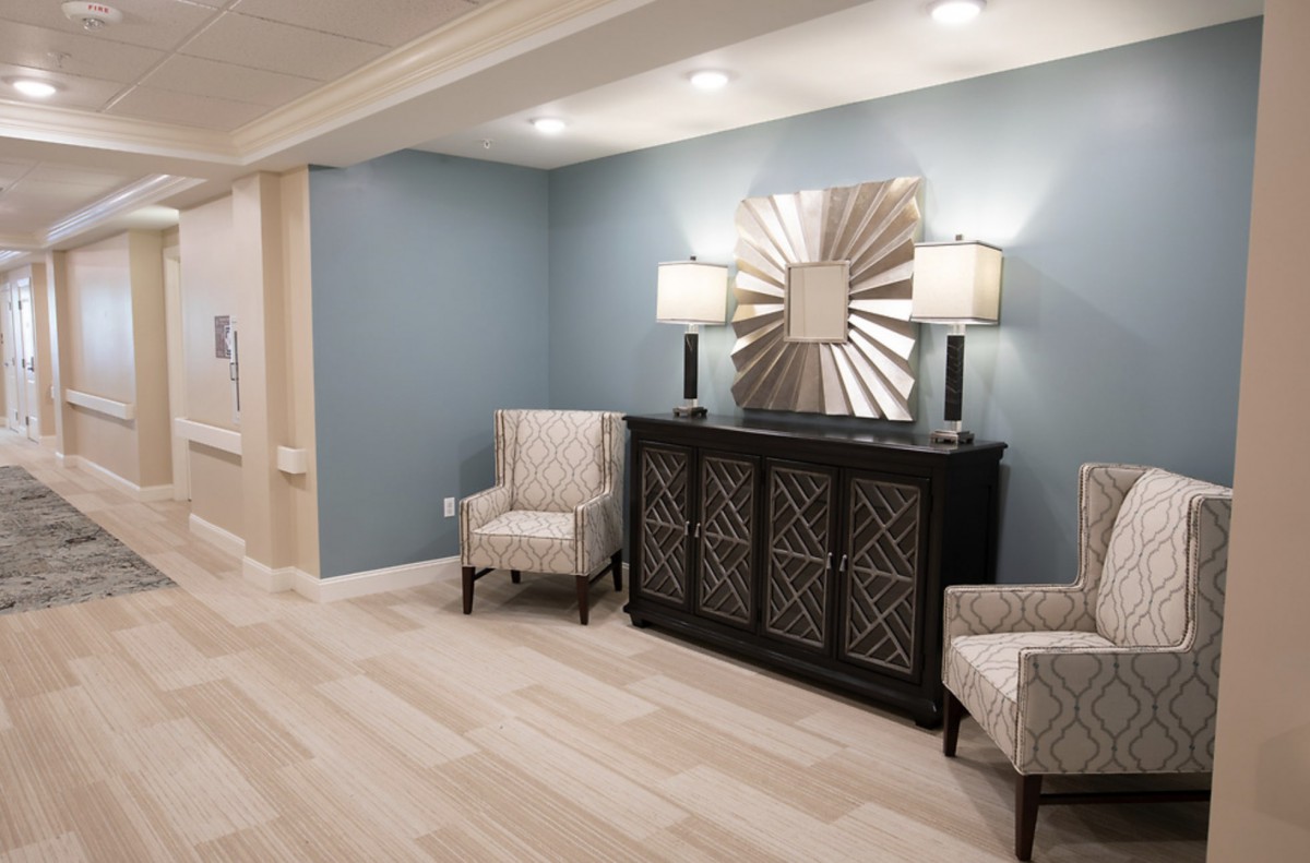 A modern living room setup with stylish furniture, featuring a decorative mirror and lamps.