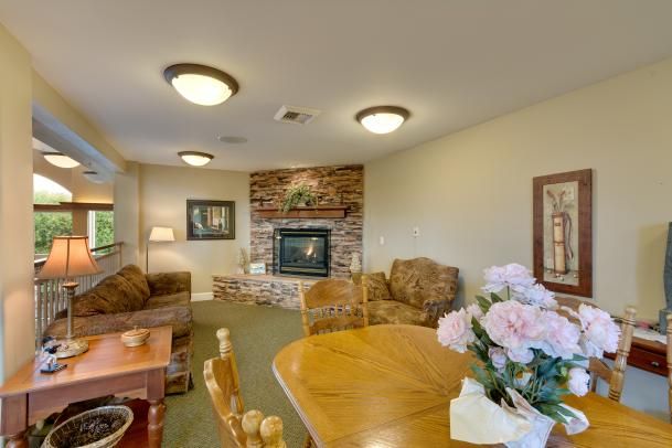 A cozy living room with a fireplace, sofas, and a dining table adorned with flowers.