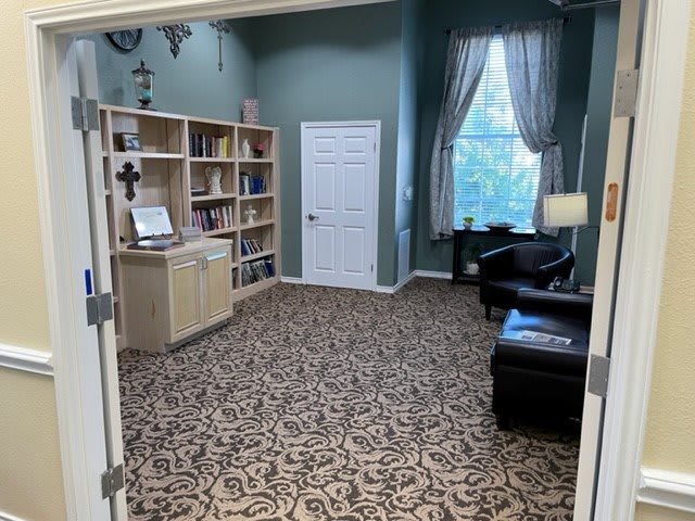 A cozy office space with a bookshelf, armchair, and warm lighting.