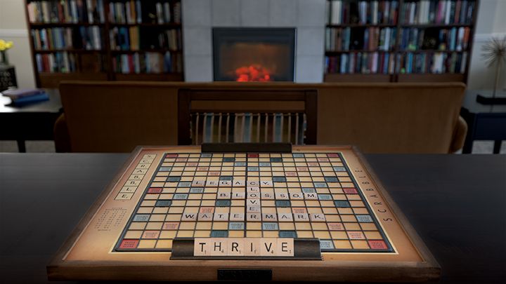 A Scrabble board set up with the word 'THRIVE' in a cozy library setting.