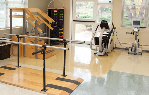 A physical therapy room equipped with parallel bars and exercise machinery for rehabilitation.