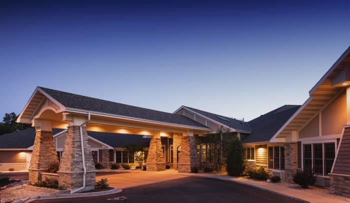 A well-lit building entrance at dusk with a stone facade.