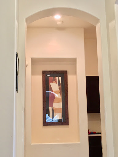 A view of a well-lit hallway featuring an abstract framed artwork.
