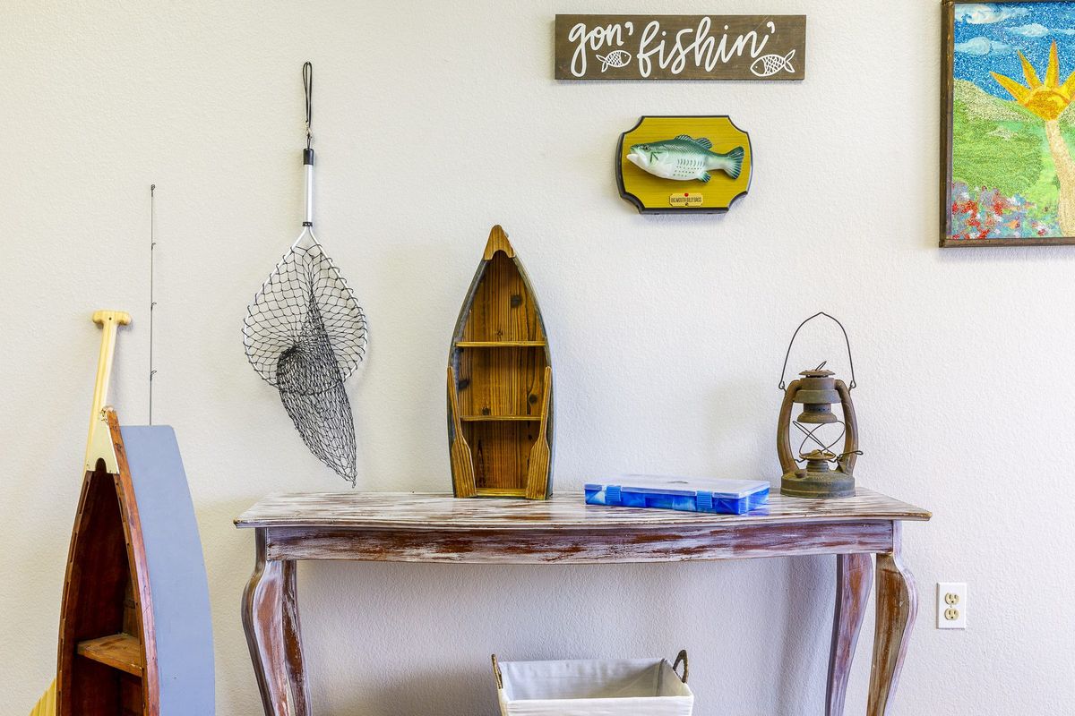 A fishing-themed decor setup featuring a rustic wooden table, a boat-shaped shelf, wall signage, and a decorative net.