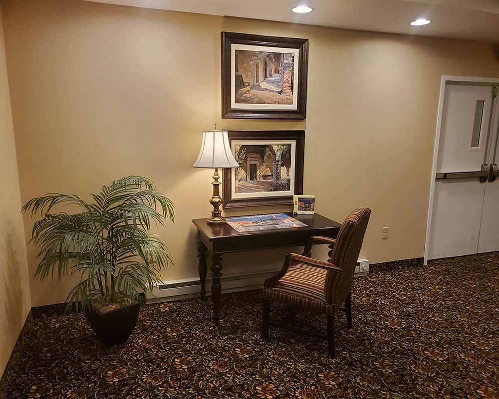 A cozy hotel lobby corner with a desk, chair, and decorative elements.