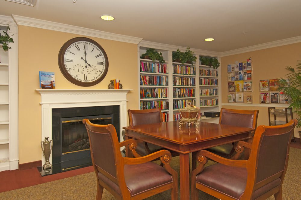 A cozy reading room with a large clock, bookshelves, and comfortable seating.