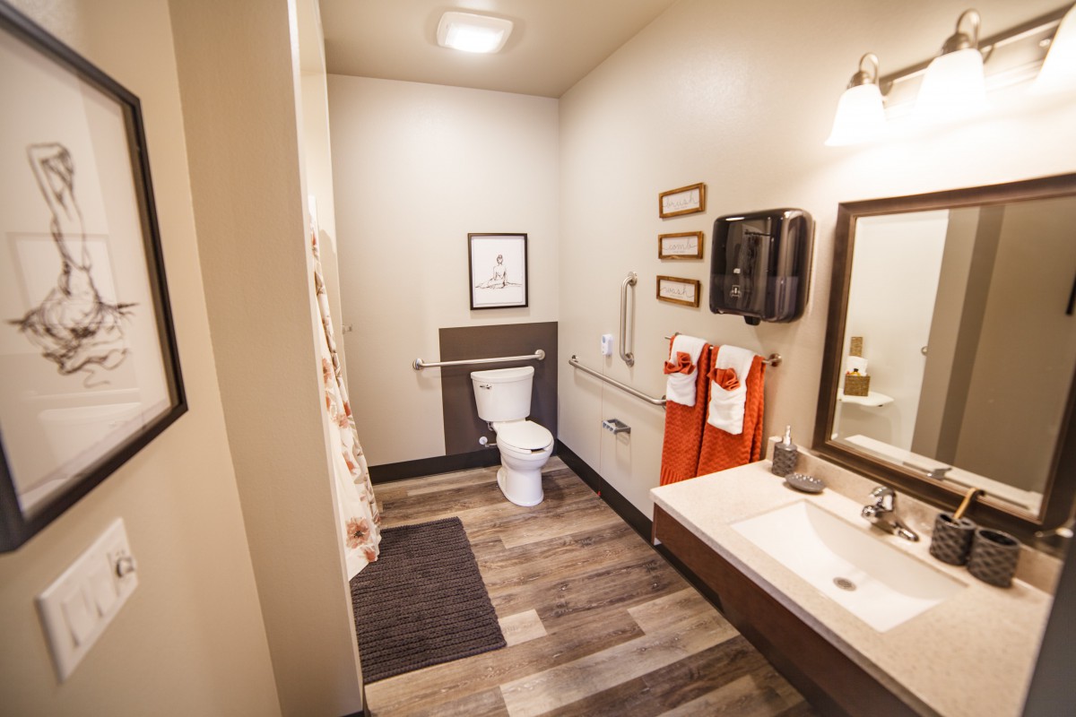 A neatly organized bathroom featuring a toilet, sink, and mirror with elegant decor and warm lighting.