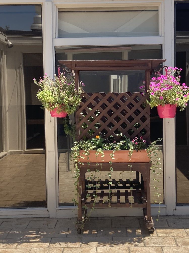 A beautifully decorated patio area features hanging flower pots and a planter box filled with colorful blooms, creating an inviting outdoor space at night.