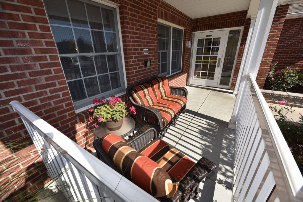 A cozy porch area with striped cushioned seating and floral decorations.