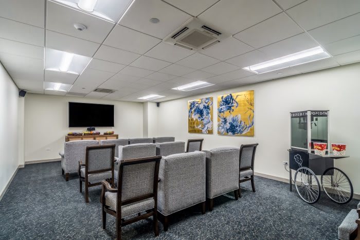 A modern meeting room with rows of chairs facing a TV screen and decorative artwork on the walls.