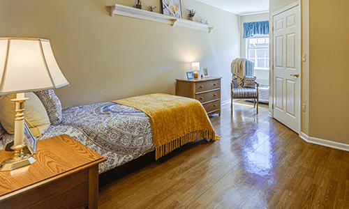 A cozy bedroom with wooden flooring and neatly arranged furniture.