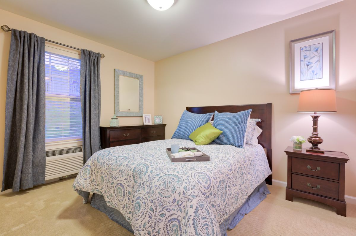 A cozy bedroom with a neatly made bed, pillows, and neutral decor.