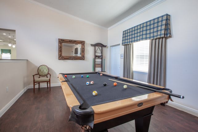A well-lit game room featuring a pool table with colorful balls ready for play.